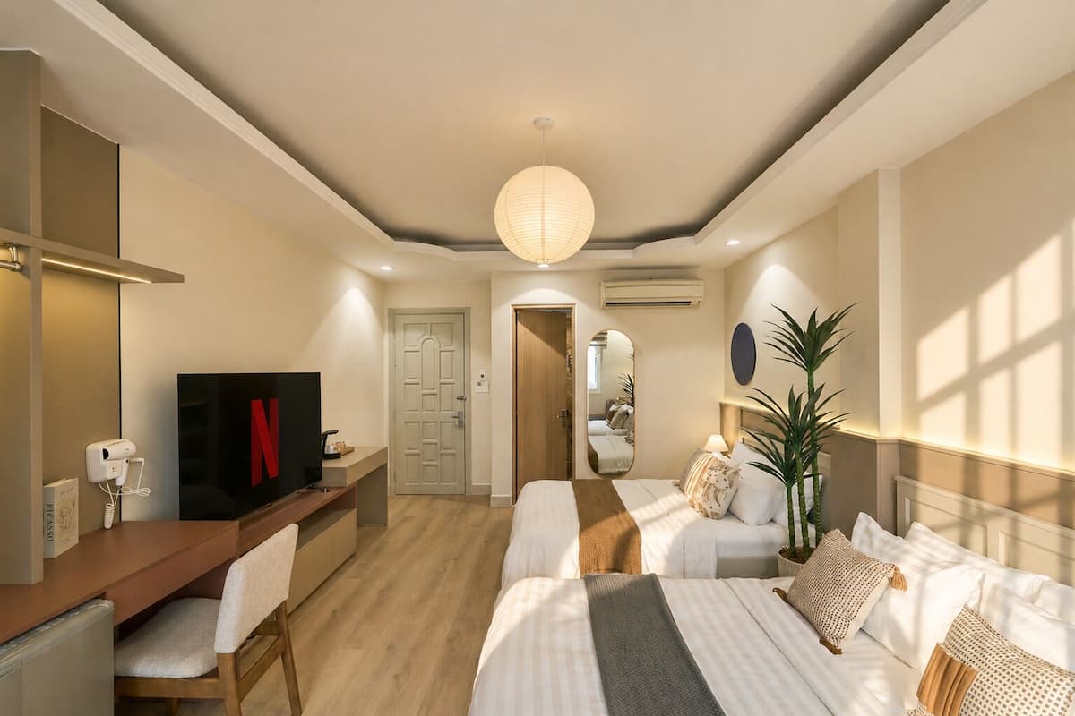 A hotel room with a bed, bedside table, TV, desk, chair, and a mirror.