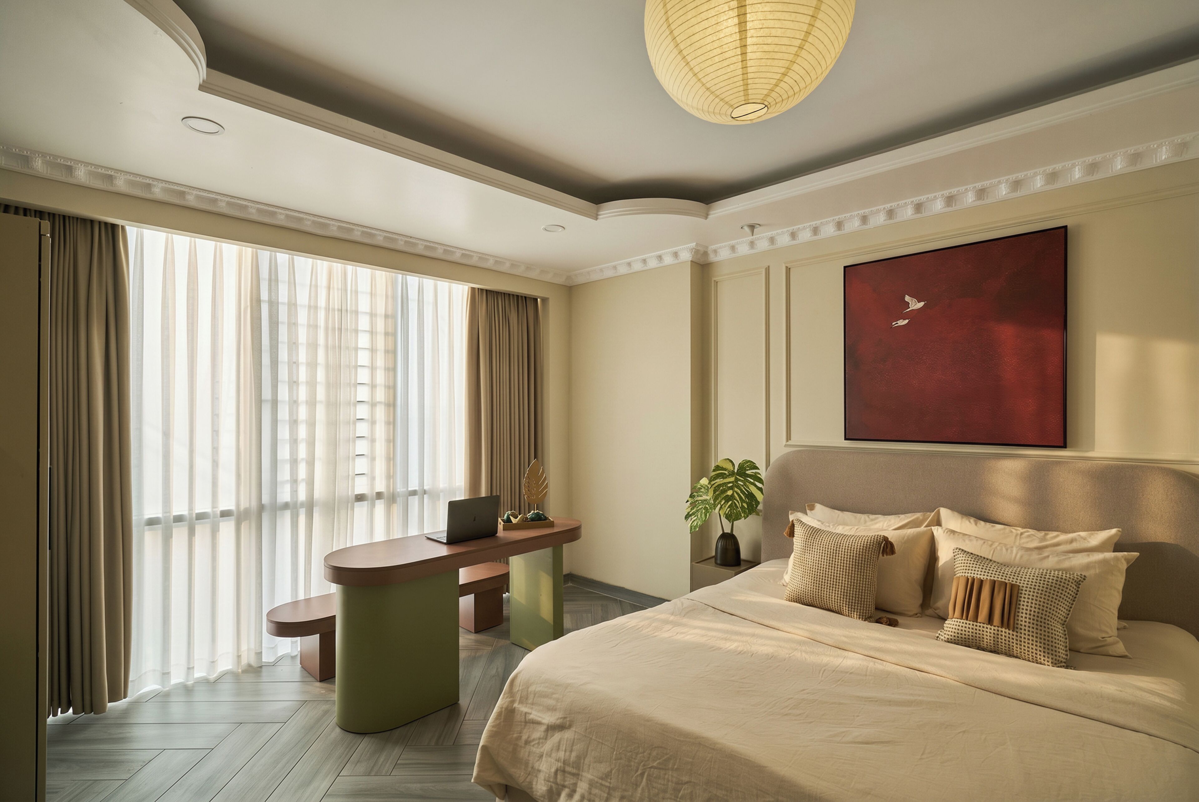 A hotel room with a bed, a desk with a laptop, a large window with curtains, and a red painting on the wall.