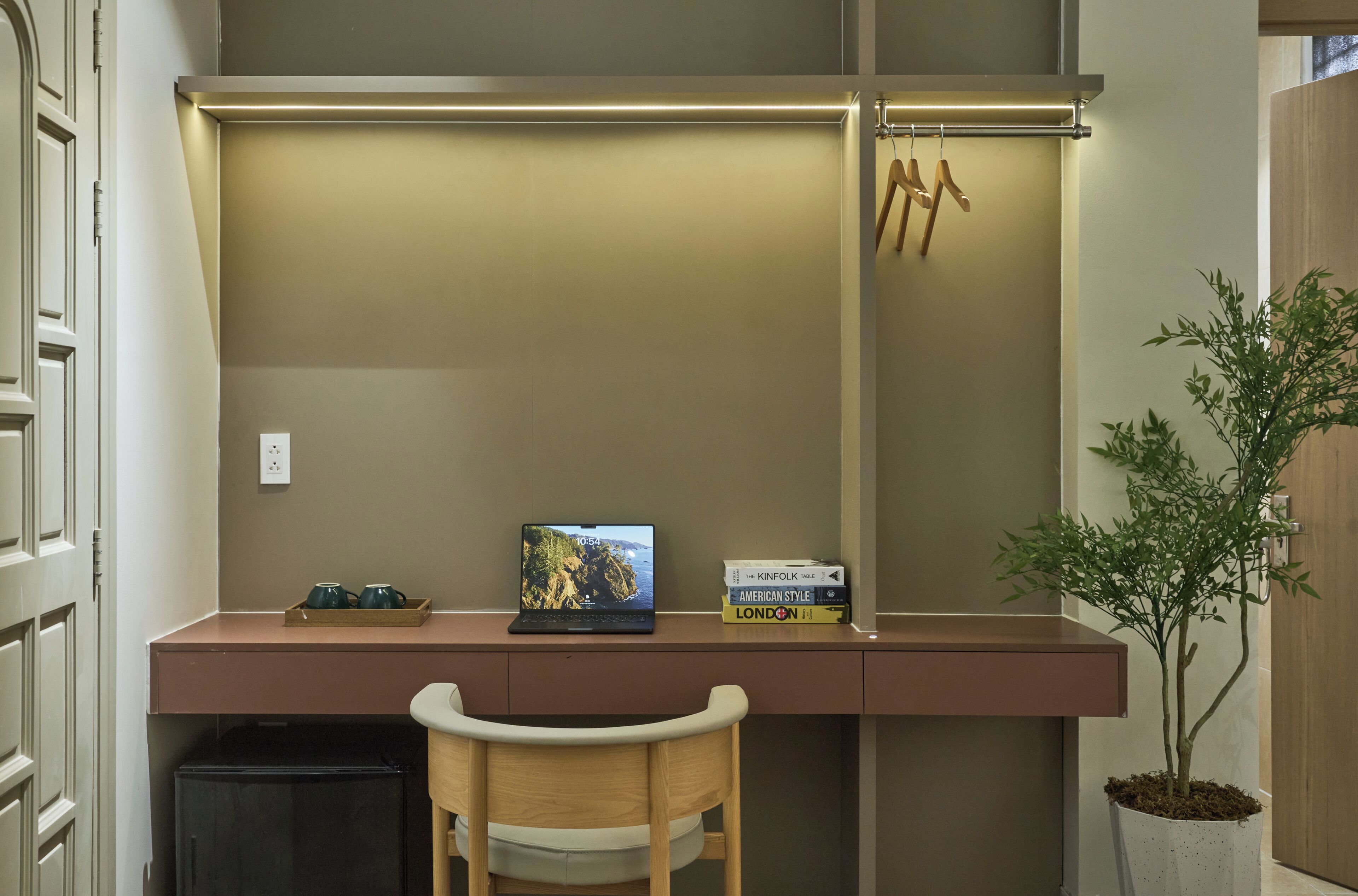A compact workspace with a laptop, books, and a potted plant.