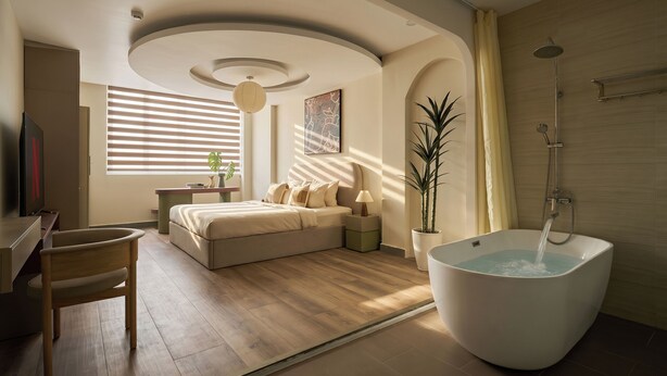 A modern bedroom with a large bed, a bathtub, and a desk. - Linh Dan Hotel Phan Xich Long By Urban B (Ho Chi Minh City)