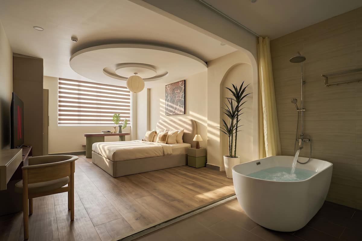 A modern bedroom with a large bed, a bathtub, and a desk.
