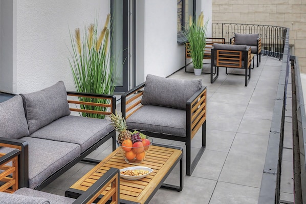 A balcony with outdoor seating, a table with fruit and snacks, and potted plants. - Master's Bridge - Stylish, large balcony, close to the dike, 2 parking spaces, 2 WCs (Bremerhaven)