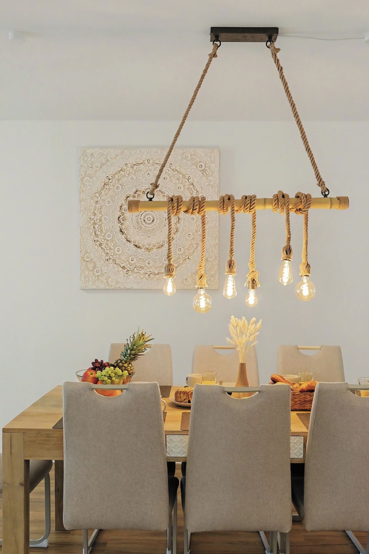Un espace repas comprenant une table en bois, des chaises et un luminaire suspendu avec des ampoules.