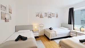 Een moderne hotelkamer met twee bedden, een nachtkastje met een lamp, een vloerlamp en kunst aan de muur.