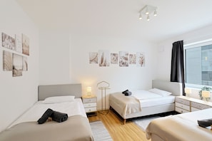 A modern hotel room with two beds, a bedside table with a lamp, a floor lamp, and artwork on the wall. - Master's Bridge - Stylish, large balcony, close to the dike, 2 parking spaces, 2 WCs (Bremerhaven)