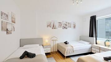 Une chambre d’hôtel avec deux lits, une table de chevet avec une lampe, un lampadaire et des œuvres d’art accrochées au mur.