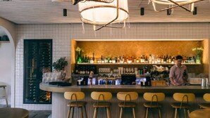 Un espace bar avec des tabourets, un comptoir avec des bouteilles et un barista.