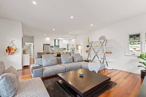 A modern living room with a sectional sofa, a coffee table, and a kitchen in the background.