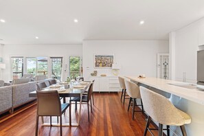 A modern kitchen with a dining area, wooden flooring, and a cityscape artwork on the wall.