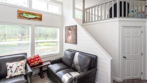 Un salon avec un canapé en cuir, un banc et un escalier doté d’une rampe.