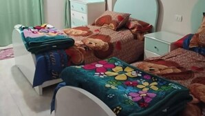 Quarto com duas camas, ventoinha no teto, cômoda e espelho.