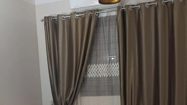 Uma sala de estar com sofá, apoio para os pés e tapete estampado.