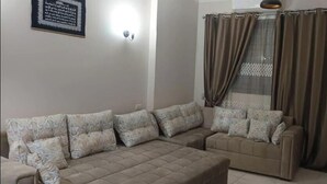 Sala de estar com sofá seccional, mesa de centro e luminária fixa na parede.