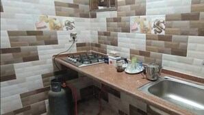Cozinha com fogão a gás, pia e painel de azulejos.