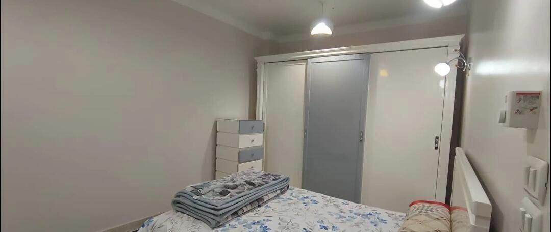 Ein Schlafzimmer mit Bett, Kommode, Kleiderschrank und Nachttischlampe.
