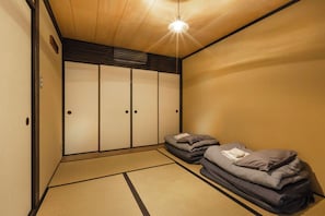 A traditional Japanese room with tatami flooring, a low ceiling, and a sliding door with a light fixture above. - A very special tea house: Ochaya Hasu (Kyoto)