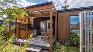 Un espace cuisine extérieur moderne, doté d’une pergola en bois, d’un barbecue encastré et d’un coin salon.