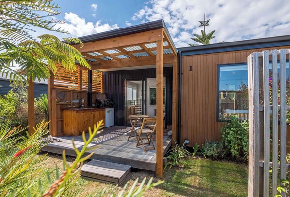 A modern outdoor kitchen area with a wooden pergola, a built-in barbecue, and a seating arrangement.