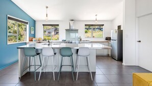 A modern kitchen with a large island, bar stools, and a view of the outdoors.