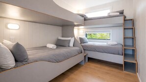 Ein Schlafraum mit Etagenbetten, einem Fenster, Holzboden und einer eingebauten Ablage.