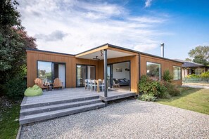 A modern house with a covered patio, a dining area, and a visible bedroom.
