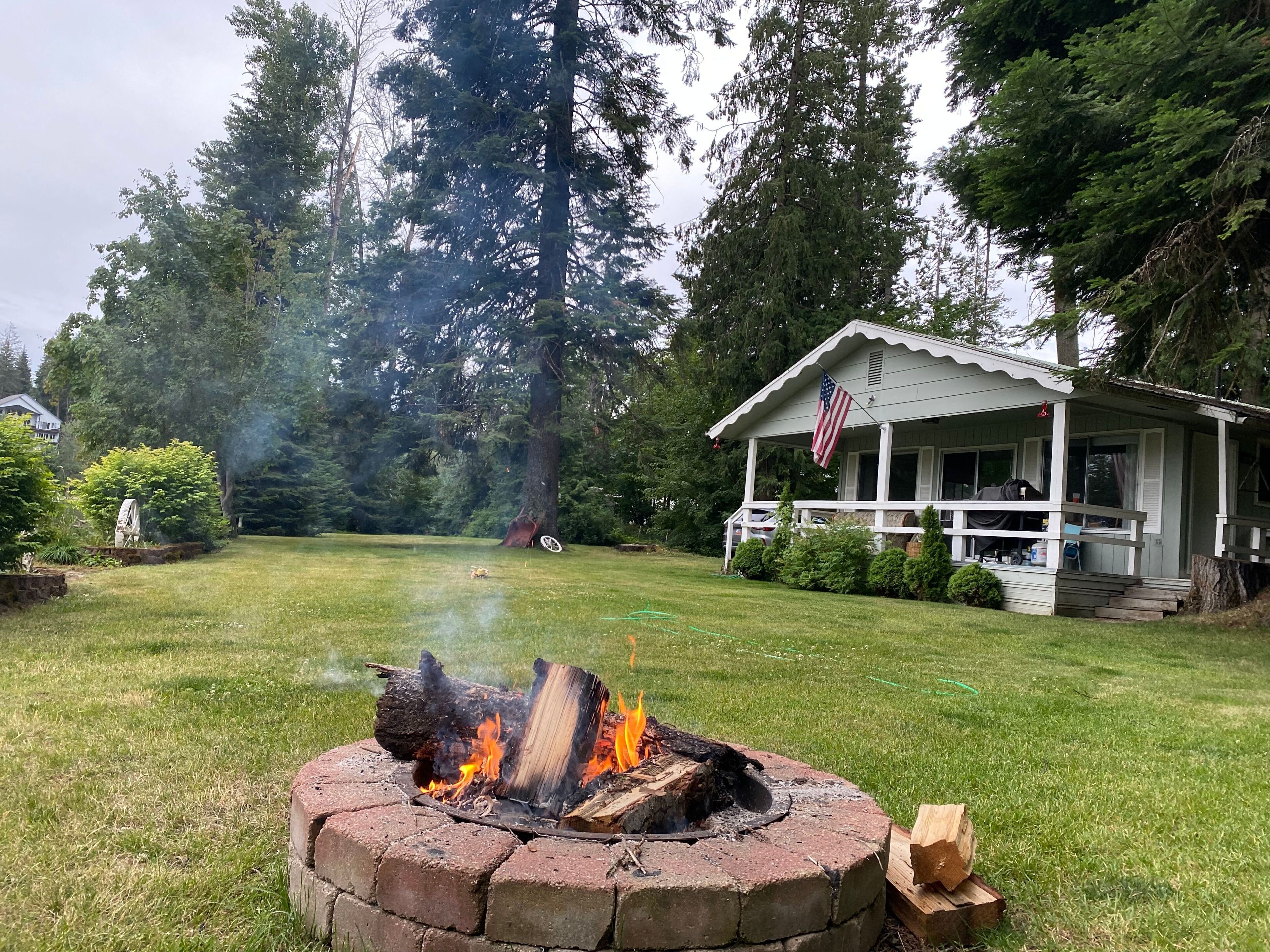 A fire pit in a grassy yard with a house in the background.