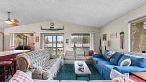 Ein Wohnzimmer mit einer Couch, einem blauen Sofa, einem Couchtisch und einem Essbereich mit einem Barhocker.