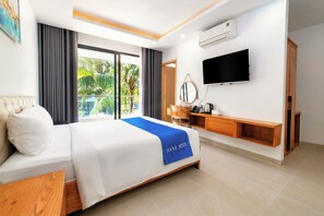 A hotel room with a bed, a desk, a TV, and a view of palm trees. - HANA HOTEL SONASEA NIGHT MARKET PHU QUOC (Phu Quoc)