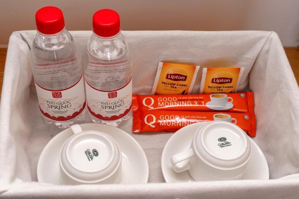 A tray with two bottles of Phu Quoc Spring water, two Lipton Yellow Label tea packets, and two sets of Lipton Good Morning 3 in 1 tea sachets.