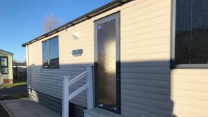 A mobile home with a front door, a small set of steps, and a window. - Charming Holiday Park Retreat in Morecambe - Family-Friendly Escape (Morecambe)
