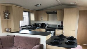 A compact kitchen with a central island, a sofa, and a dining table. - Charming Holiday Park Retreat in Morecambe - Family-Friendly Escape (Morecambe)