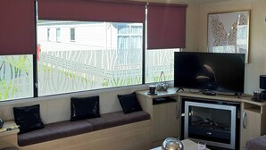 A living room with a sofa, a television, a coffee table, and a fireplace. - Charming Holiday Park Retreat in Morecambe - Family-Friendly Escape (Morecambe)