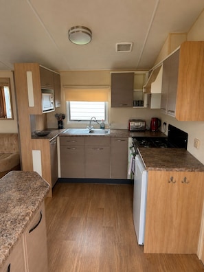A compact kitchen with a sink, stove, and cabinets. - Singh&Leite Family L6 (Clacton-on-Sea)