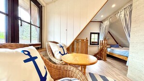Une pièce chaleureuse avec un canapé en osier, une petite table ronde et un lit à baldaquin.