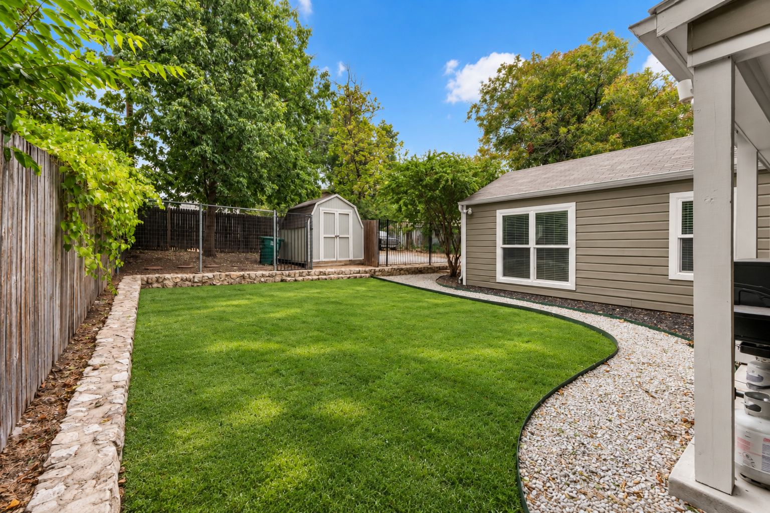 A backyard with a lawn, a shed, and a house.