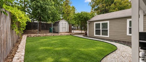 A backyard with a lawn, a shed, and a house.