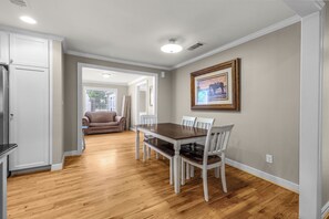 A dining area with a wooden table and chairs, a framed picture on the wall, and a kitchen area with cabinets and a refrigerator. - Cozy home in Ft Worth, walk to Dickies Arena & Will Rogers Coliseum horse show (Fort Worth)
