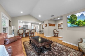 A spacious living area with a brown leather sofa, a wooden coffee table, and a large flat-screen TV mounted on the wall. - Cozy home in Ft Worth, walk to Dickies Arena & Will Rogers Coliseum horse show (Fort Worth)
