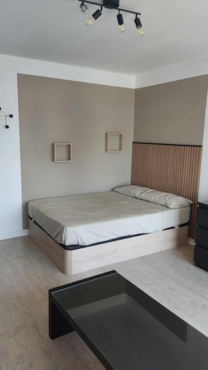 Ein modernes Schlafzimmer mit Bett, Nachttisch und Wandleuchte.