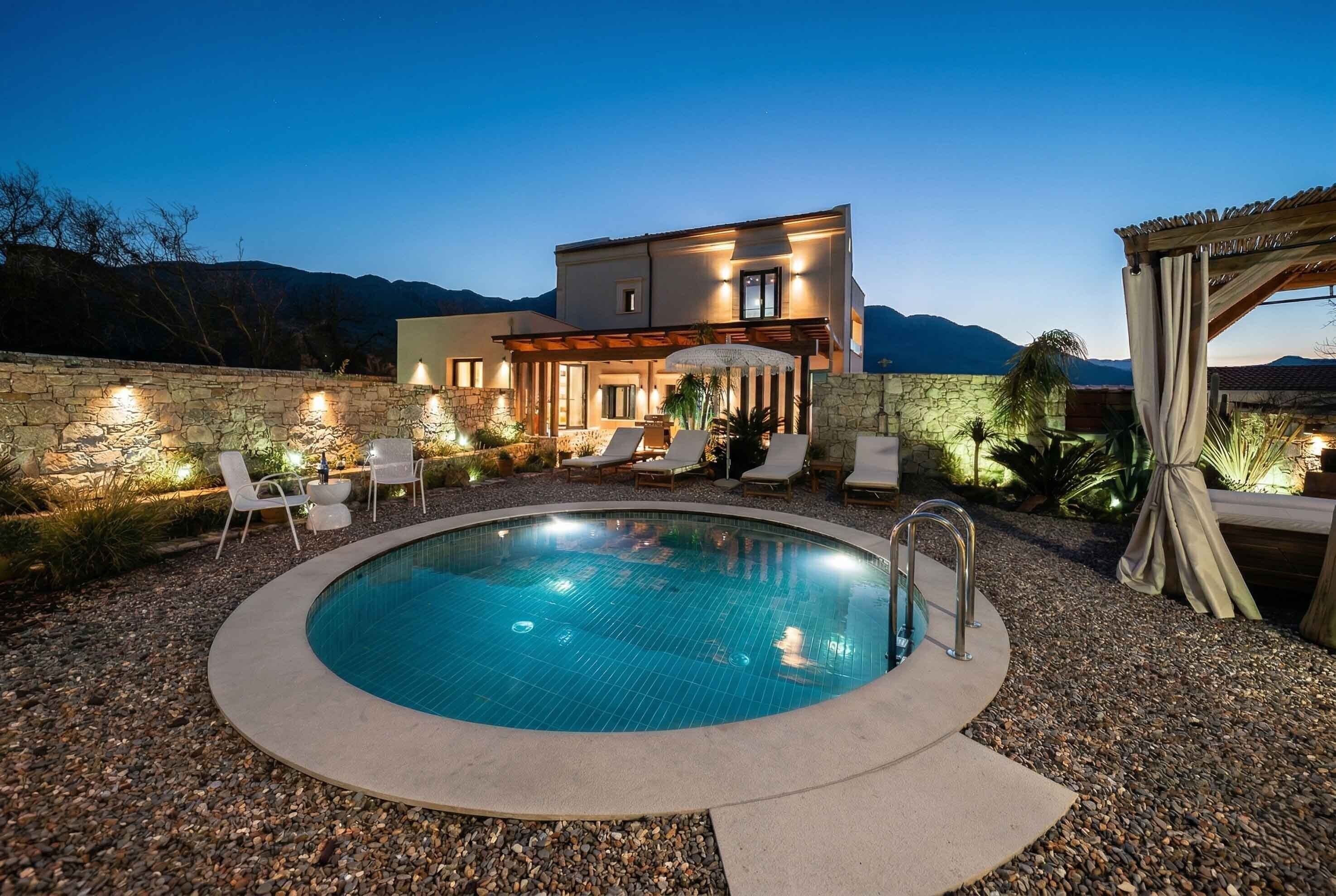 A modern pool area with a stone wall, lounge chairs, and a building with a stone facade.