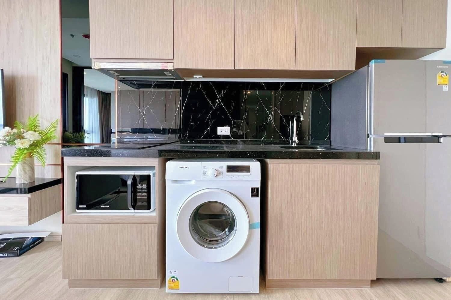 A compact kitchen with a built-in washer, microwave, and refrigerator.