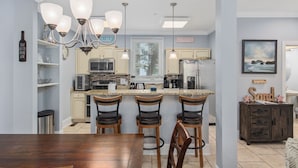 Una cocina moderna con una isla central, taburetes de bar y una mesa de comedor.