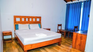 Una cama de madera con ropa de cama blanca, una mesita de noche de madera, un escritorio de madera y una silla.