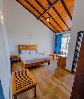 Un dormitorio con techo de madera, una cama, una mesita de noche, un banco y una ventana con cortinas.