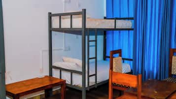 Una cama litera con escalera, una mesa de madera y una silla en una habitación con cortinas azules.