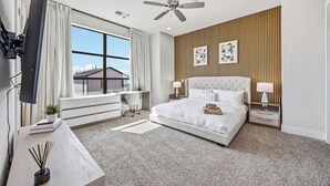 A modern hotel room with a large bed, a desk, a TV, and a ceiling fan. - Luxury 3Bed/3.5Bath Townhome 10 Minutes from Downtown HTX (Houston)