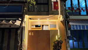 Un immeuble de deux étages doté d’un balcon, d’une porte portant le numéro « 61 » et d’un pot de fleurs placé devant l’entrée.