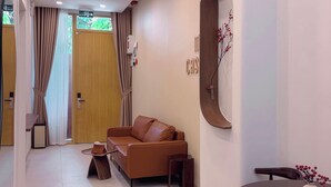 Une chambre d’hôtel moderne équipée d’un canapé, d’une table à manger, d’un miroir et d’une porte en bois.