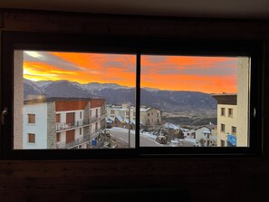 A view through a window of a town with buildings and mountains in the background. - Pilgrim's Cabin - A breathtaking view and close to everything! (Font-Romeu-Odeillo-Via)