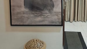 Ein gerahmtes Kunstwerk mit gestapelten Steinen, Vögeln, einem Korbwäscher und einem Vorhang.